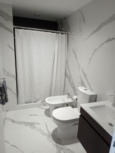 ein weißes Badezimmer mit Toilette und Waschbecken in der Unterkunft Despertar Frente al Mar in Puerto Madryn