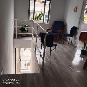 a living room with a staircase and two chairs at Aparta Hostal in Santa Rosa de Cabal