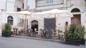 a group of tables and chairs with umbrellas in front of a building at Barbahouse in Monte SantʼAngelo