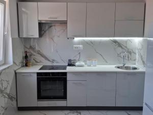 a white kitchen with a sink and a stove at Milovic Apartman in Kotor