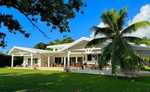 a palm tree in front of a white house at Hokulea - Propriété bord de mer in Uturoa