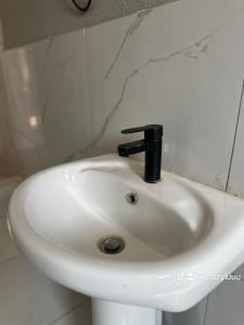 a white sink with a black faucet in a bathroom at Rose's Lodge in Ga-Selala