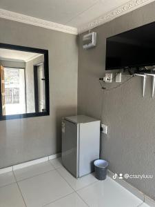 a small refrigerator in a room with a window at Rose's Lodge in Ga-Selala +10 photos