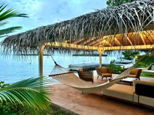 a hammock in a pavilion with a view of the water at Hokulea - Propriété bord de mer in Uturoa