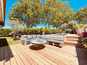 a patio with a couch and a table on a deck at Maison avec piscine-climatisation-jardin in Ventenac en Minervois