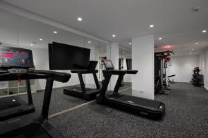 a gym with cardio equipment and a television in a room at Nuca Mykonos Hotel in Platis Gialos