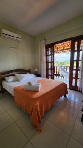 a bedroom with a bed with an orange blanket at Linda casa com excelente localização em Boipeba in Ilha de Boipeba +12 photos