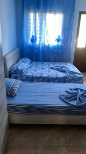 a bedroom with two beds with blue sheets and a window at Hotel Marino in Baks-Rrjoll