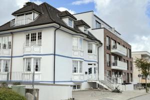 un edificio bianco con tetto nero di CuxHeaven - modernes Studio-Apartment direkt am Meer mit 65 Zoll TV und Tiefgarage in Duhnen a Cuxhaven