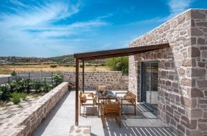 a patio with a table and chairs on a stone wall at Livadi Resort in Adamas