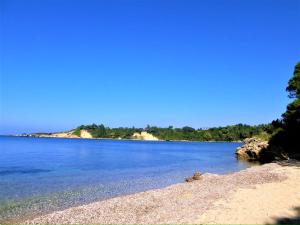 a beach with blue water and trees in the background at Harmony Home in Pyrgos