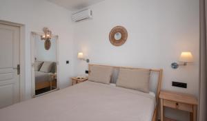 a bedroom with a white bed and a mirror at Livadi Resort in Adamas