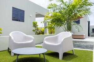 twee witte stoelen en een tafel in een tuin bij Villa Kura Cura - 5 Minutes From Mambo Beach in Willemstad