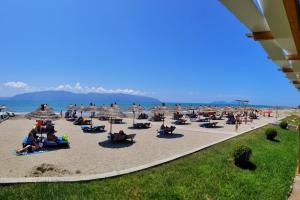 a group of people sitting on a beach with umbrellas at Vila Green Relax in Vlorë