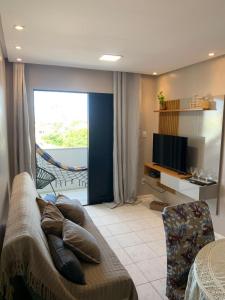 a living room with a couch and a television at Ap Confortável e Acolhedor perto da Orla Atalaia in Aracaju