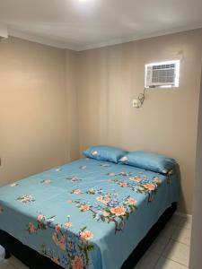 a bed with a blue bedspread with flowers on it at Ap Confortável e Acolhedor perto da Orla Atalaia in Aracaju
