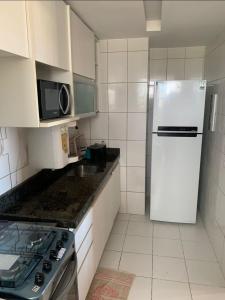 a white kitchen with a refrigerator and a microwave at Ap Confortável e Acolhedor perto da Orla Atalaia in Aracaju