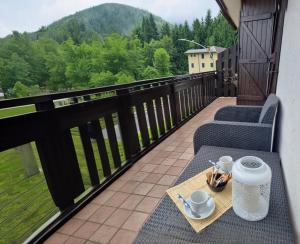 un balcone con 2 sedie e un tavolo con tazze di caffè di La Casa degli Sbilfs - Wi-Fi, Netflix e Garage Box , a 2 minuti dallo Zoncolan a Ravascletto