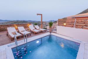 a swimming pool with two chairs and a deck at Pavlos & Sofia Villa Vigla - Heated Private Pool in Ágios Matthaíos