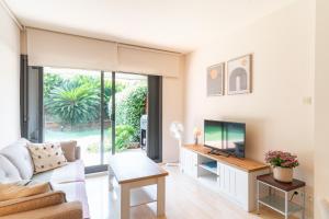 a living room with a couch and a tv at Charming Garden Apartment en "Jardins de Sa Boadella" in Lloret de Mar