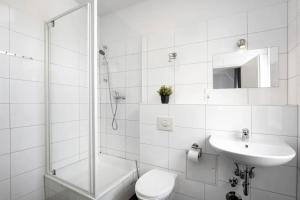 a white bathroom with a toilet and a sink at Apartments Tempelhof in Berlin +101 photos