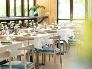 a dining room with white tables and chairs at DeeProm Pattaya Hotel in Pattaya