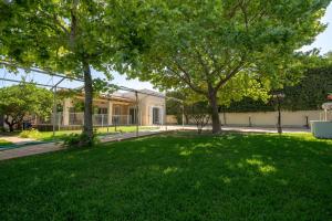 a green yard with trees in front of a building at G&A Family Home near the Beach by MΡS in Nea Makri