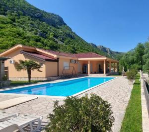 a house with a swimming pool in front of a mountain at Hacienda Neretva in Buna