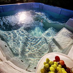 a pool of water with a plate of fruit in it at Osada Miłojeż - całoroczne Domy Premium w Borach Tucholskich, Jacuzzi pod gwiazdami in Gostycyn