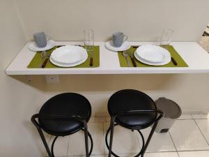 a table with two chairs and plates and glasses at Loft 220 Ar Cond Wi-fi com Box TV filmes e séries in Niterói