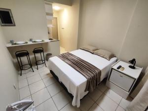 a small bedroom with a bed and a small kitchen at Loft 220 Ar Cond Wi-fi com Box TV filmes e séries in Niterói