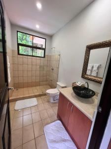 a bathroom with a sink and a toilet and a mirror at Villa Montana in Tarcoles