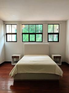 a bedroom with a large bed with three windows at Villa Montana in Tarcoles