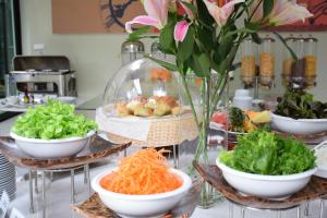 a buffet with bowls of vegetables and a vase of flowers at Annex Lumpini Bangkok in Bangkok