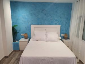 ein Schlafzimmer mit einem weißen Bett mit einer blauen Wand in der Unterkunft Casa pepa in Marbella