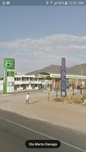 Casa Hotel Marly في سانتا مارتا: رجل يسير في الشارع أمام محطة وقود