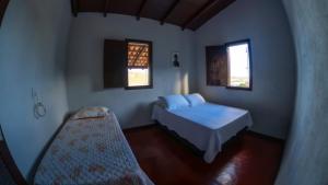 a bedroom with a bed and two windows at Casa junto as montanhas in Capitólio +92 photos