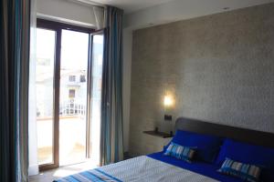 una camera con un letto blu e una grande finestra di Terrazzi in Fiore ad Alghero