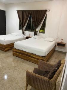 twee bedden in een kamer met een stoel en een bank bij Bellooceano in Playa del Carmen