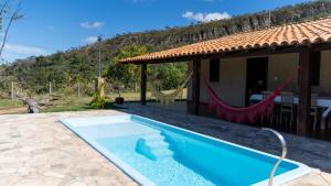 a villa with a swimming pool in front of a house at Casa junto as montanhas in Capitólio