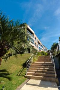 a building with stairs and a palm tree in front at Florianópolis Costão das Gaivotas Santinho in Florianópolis