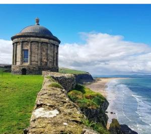 an old building on a cliff next to the ocean at TheWeeHouseOnTheHill in Kilrea