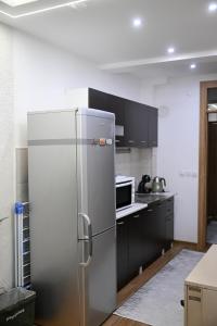 a stainless steel refrigerator in a kitchen with black cabinets at Hanan Apartmani in Novi Pazar