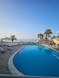 a large swimming pool with palm trees and the ocean at Eleni Beach Apartment in Stalís