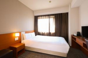 a hotel room with a bed and a window at Dormy Inn Kurashiki Natural Hot Spring in Kurashiki