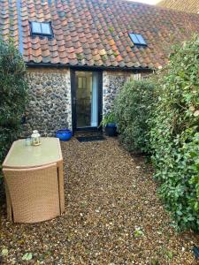a table in front of a house with a roof at Barnacle Barn, North Norfolk in Roughton