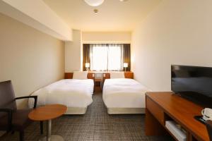 a hotel room with two beds and a flat screen tv at Dormy Inn Kurashiki Natural Hot Spring in Kurashiki