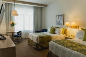 a hotel room with two beds and a table and a couch at Hotel San Marcos Grand in Culiacán