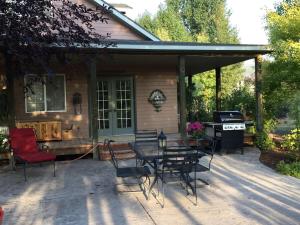 a patio with a table and chairs and a grill at Wildland Gardens Farm House w Private Hot tub in Joseph