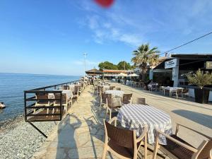 una fila de mesas y sillas junto al agua en Fanis Rooms, en Kokkino Nero